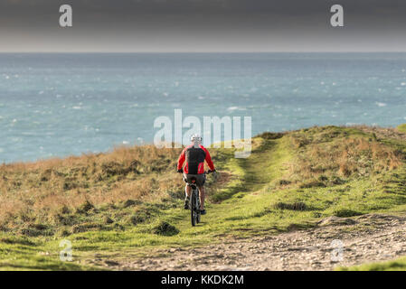 Mountainbiken - ein Radfahrer, Mountainbiker, ein Mountainbike über einen Fußweg auf der East Pentire Newquay Cornwall im Vereinigten Königreich. Stockfoto