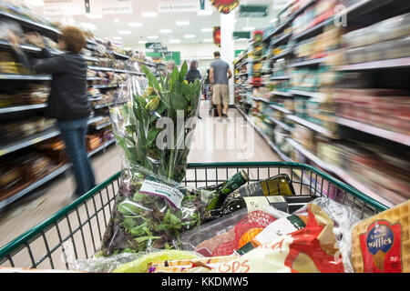 Einen Einkaufswagen voller Waren nach unten gedrückt wird, um einen Gang in einem Supermarkt. Stockfoto