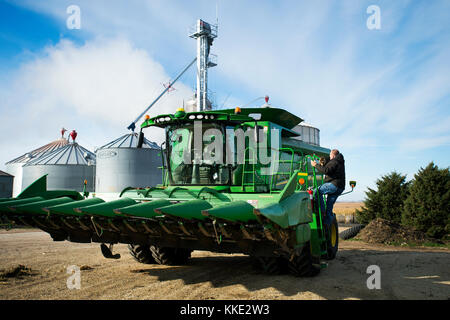 Landwirt KLETTERN IN SEINEN JOHN DEERE MÄHDRESCHER WIE BEREITET ER ZUR ERNTE VON MAIS AUF DEM LAND, DAS ER MIT SEINEM VATER IN Utica, Minnesota. Stockfoto