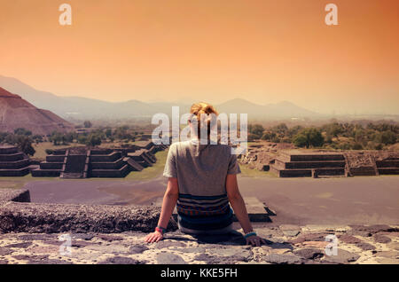 Junge Frau sitzt an der Spitze der Pyramide und mit Blick auf Teotihuacan Ruinen Stockfoto