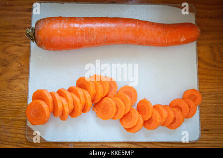 Blick von oben auf frisch gehackte OrangenKarotten auf einem Schneidebrett, bereit zum Kochen. Gesunde Lebensmittelzubereitung, Mahlzeit Vorbereitung, und Rezept Tutotorials. Stockfoto