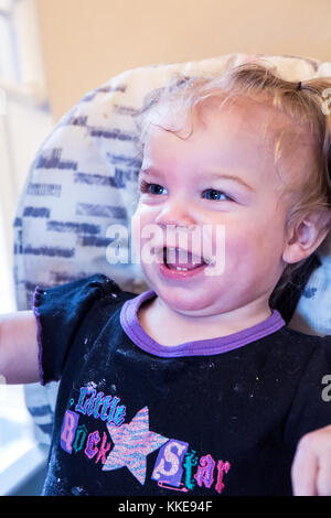 Glückliches Mädchen auf ihrem ersten Geburtstag, nachdem ihr Kuchen essen Stockfoto