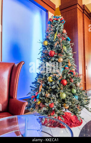 Geschmückten Weihnachtsbaum neben einem bunten Leuchtplatte im Renaissance Hotel Lobby in Montgomery, Alabama, USA. Stockfoto