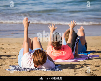 Ältere spanische Frauen dehnen sich täglich beim Yoga/Stretching am Strand. Stockfoto