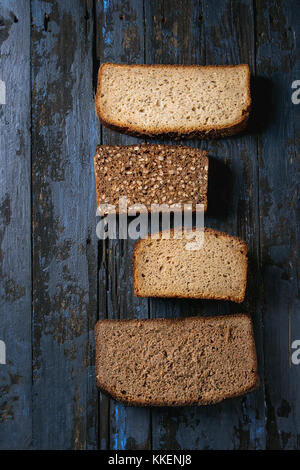 Verschiedene Brote in Scheiben hausgemachtes Roggenbrot Vollkorn und Samen über Altes, dunkles Holz- Hintergrund. top View, Platz. gesunde Ernährung Stockfoto