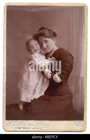 Edith Johnson und Baby Beryl, 1910, Edith Johnson war Edith Willatt, 1879 geboren. Sie heiratete William Johnson, ein paar Jahre älter als sie, und sie war seine zweite Frau. Sie hatten eine Tochter, Beryl Edith Alice, 1910 geboren. Das ist eine formale Studio Portrait von Mutter und Kind, wenn Beryl etwa acht Monate alt war, von W.E. Wright und Söhne, die gestaltete sich 'Hochformat, Gruppe und Architekturfotografen, mit Studios in Forest Gate, Ilford, sieben Könige, Romford, Leyton, Walthamstow und Hamlet Court Road, Westcliff, wo das Foto gemacht wurde. Stockfoto