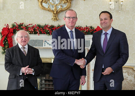 Taoiseach Leo Varadkar (rechts) schüttelt Hände mit der neu ernannte Stellvertretende Premierministerin Simon Coveney (Mitte) während der irische Präsident Michael D Higgins auf bei den Aras in Dublin aussieht, nach dem Rücktritt von Frances Fitzgerald über ihren Umgang mit der Polizei whistleblower Skandal. Stockfoto