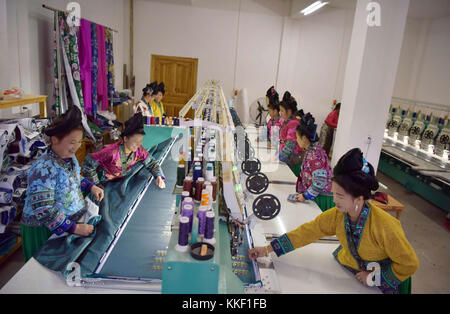 Qiandongnan, chinesische Provinz Guizhou. Dezember 2017. Frauen der ethnischen Gruppe Miao arbeiten an einer Maschine, um Stickarbeiten im Dorf Ma'an im County Congjiang, südwestchinesische Provinz Guizhou, am 1. Dezember 2017 zu machen. Das Computerdesign und die mechanische Arbeit haben dazu beigetragen, die traditionelle handgefertigte Stickerei zu verändern. Quelle: Wu Dejun/Xinhua/Alamy Live News Stockfoto