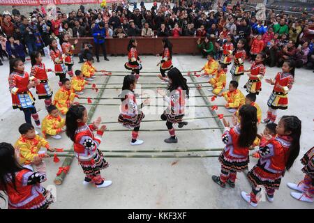 Rongjiang, chinesische Provinz Guizhou. Dezember 2017. Kinder der ethnischen Gruppe Yao spielen Bambustanz anlässlich des Panwang Festivals im Dorf Tashi im Bezirk Rongjiang, Provinz Guizhou im Südwesten Chinas, 3. Dezember 2017. Das Panwang Festival wird von den Yao gefeiert, um den Vorfahren Tribut zu zollen. Quelle: Yang Chengli/Xinhua/Alamy Live News Stockfoto