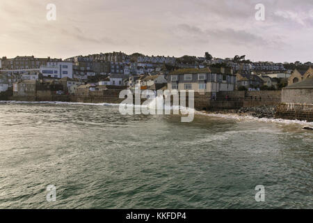 Während die Flut in St Ives einbricht, wird ein schwerer Sturm die Küstenstadt treffen, während die Wellen beginnen zu bauen und gegen die Meeresmauer krachen. Stockfoto