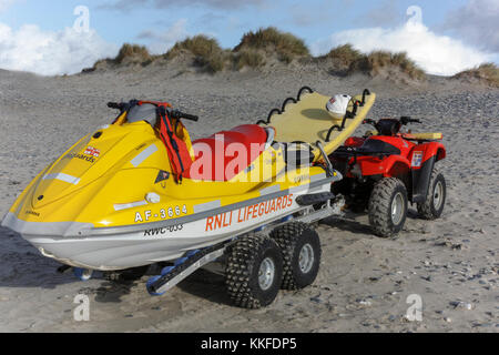 R.n.l.i Jet Ski- und Rescue Board auf einem Anhänger von einem Quad Abschleppen nicht auf die Buchen in Cornwall im Südosten von England. Stockfoto