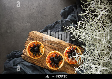 Italienische hausgemachte Mini Pizza mit Käse, Tomaten, Oliven. dunklen Hintergrund. Halloween und Spider Stockfoto