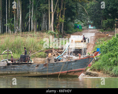 Holz- Frachtschiff entladen Kies und Steine auf einen Lkw durch Pumpen mit Wasser in einem Dorf an der tanintharyi Fluss in der tanintharyi Regi Stockfoto