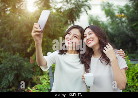 Glückliche junge Frauen Freunde gut Gekleideten lächelnd, während zusammen Stockfoto