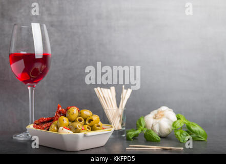 Oliven, getrocknete Tomaten und Rotwein auf grauem Stein Tabelle Stockfoto