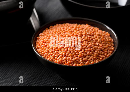 Rohe rote, getrocknete Linsen in schwarz Schüssel auf dem Tisch Stockfoto