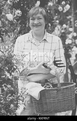 Lächelnd senior Frau Gärtner mit Gartenbau Tools arbeiten mit roten
