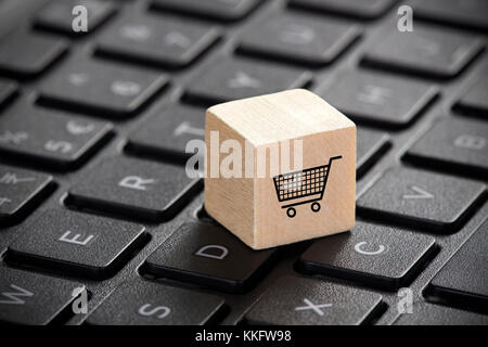 Holzblock mit Warenkorb Grafik auf Laptop Tastatur. Online shopping Konzept. Stockfoto