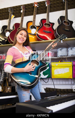 Glückliche junge Kunden kaufen neue Gitarre im Laden und lächelnd Stockfoto