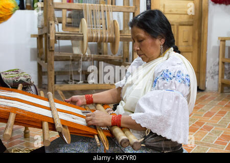 Ecuador Kultur - eine indigene Frau mittleren Alters das Weben mit einem herkömmlichen Back Strap Webstuhl, Otavalo, Ecuador, Südamerika Stockfoto