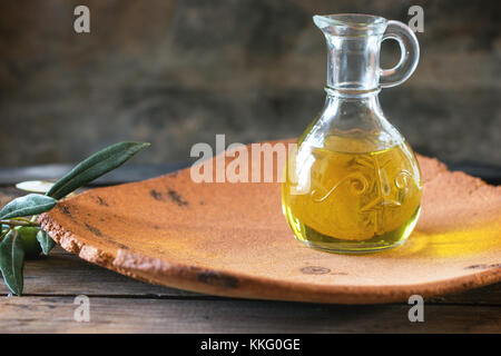 Schlacht von Olivenöl mit Olive Branch in handgefertigten Ton die Platte über der hölzernen Tisch. Stockfoto
