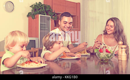 Junge lächelnde Familie von vier essen Spaghetti zu Hause Interieur. Im Mittelpunkt der Mensch Stockfoto