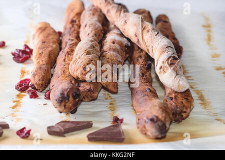 Frisch gebackenes Brot, hausgemachte süße Schokolade grissini Sticks über Backpapier auf weißen Tischdecke. Sonne Licht. Stockfoto