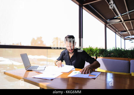 Büroangestellter sortieren Papiere auf dem Tisch in der Nähe der Räder. Stockfoto