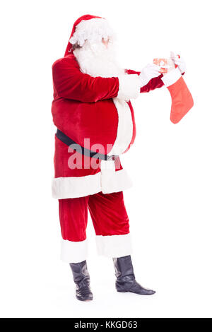 Weihnachtsmann versteckt Geschenk im Strumpf Stockfoto
