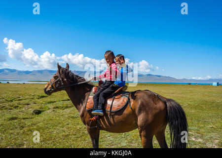 Song kul, Kirgisistan - 11. August: zwei Kinder reiten und Gruß von einem Pferd von Song Kul See. august 2016 Stockfoto