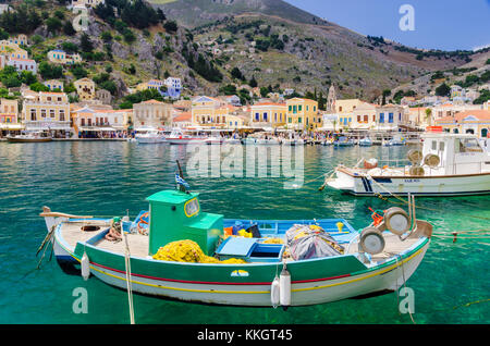 Angeln Boot in das klare Wasser Hafen von Yialos Stadt, Symi, Griechenland Stockfoto