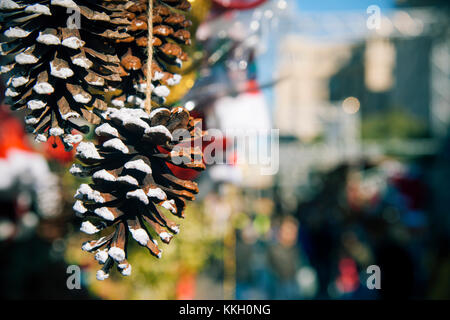 Nahaufnahme von einigen natürlichen Tannenzapfen auf Verkauf hängen in einem Stall in einem Weihnachtsmarkt Stockfoto