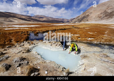 Mutter und Sohn das Berühren heißer Wasser von einem Geysir in geothermischen Bereich Puga, Ladakh, Jammu und Kaschmir, Indien. Stockfoto