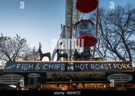 Edinburgh, Schottland, Großbritannien, 30. November 2017. Weihnachtsmarkt und Fairgroundfahrt in Edinburgh mit einem Großen Rad hinter einem Fisch und Pommes und heißem Schweinebraten an einem Imbiss-Outlet in den Princes Street Gardens Stockfoto