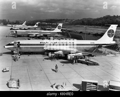 "AUF DER FLUGLINIE in Seattle, Washington, stehen die ersten drei 707-121 Flugzeuge mit Pratt & Whitney JT3C6-Triebwerken, die 1958 an Pan American World Airways geliefert werden. Das Flugzeug N711PA (Vordergrund) war der Jetliner, der am 26. Oktober 1958 mit einem Flug zwischen New York und Paris den ersten regulären US-Jet-Transport einweihte." Linke Seitenansicht von etwas über dem Boeing Modell 707-121 (r/n N711PA) auf der Boeing-Werksfluglinie in Seattle, Washington. Im Hintergrund sind r/n N710PA (Mitte) und darüber hinaus zu sehen, r/n N709PA; eine U.S. Air Force Boeing B-52 Stratofortress ist zu sehen Stockfoto