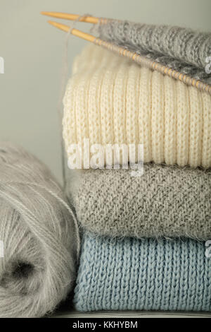 Handarbeit, Stricken und Wolle thread. Stapel aus Gewirken Kleider blauen, weißen und grauen Farben. Selektive konzentrieren. Stockfoto