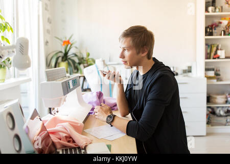 Fashion Designer mit Smartphone Arbeiten bei Studio Stockfoto