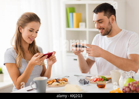 Paar mit Smartphones Frühstück zu Hause in Stockfoto