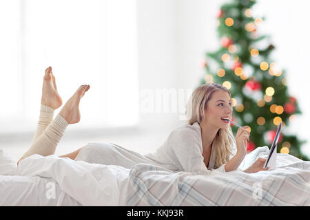 Frau mit Notebook im Bett zu Weihnachten Stockfoto