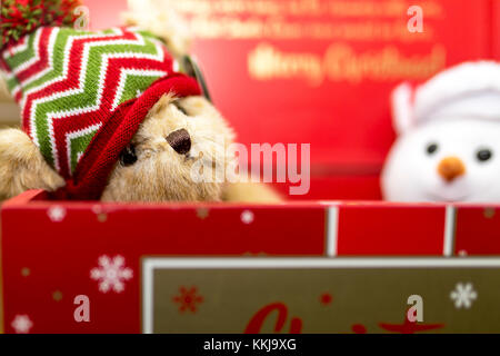 Vintage festliche braun Teddy trägt dann eine Wollmütze in einem roten Weihnachten Geschenk Box mit weichem Plüsch Schneemann Stockfoto