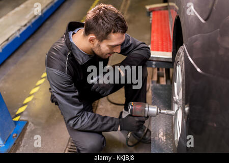 Automechaniker mit Schraubendreher ändern Autoreifen Stockfoto