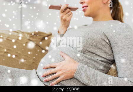 Schwangere Frau mit Voice-Recorder auf smartphone Stockfoto