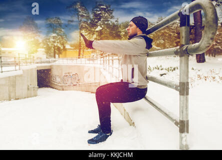 Sport Mann hockt am Zaun im Winter Stockfoto