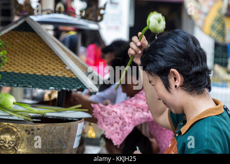 Bangkok, Thailand. Anbeter Besprengung heiliges Wasser auf dem Kopf mit einem Lotus Blossom, Royal Grand Palace Compound. Stockfoto