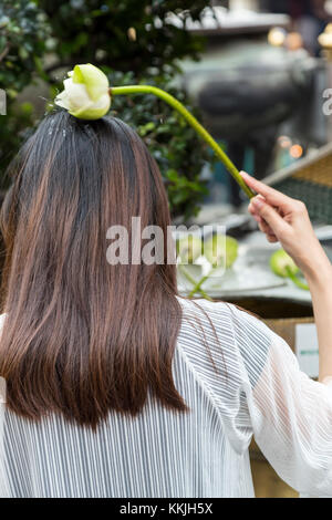 Bangkok, Thailand. Anbeter Besprengung heiliges Wasser auf dem Kopf mit einem Lotus Blossom, Royal Grand Palace Compound. Stockfoto