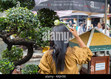 Bangkok, Thailand. Anbeter Besprengung heiliges Wasser auf dem Kopf mit einem Lotus Blossom, Royal Grand Palace Compound. Stockfoto