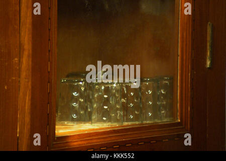 Schrank mit Glaswaren, viele Glas Schale sind in den Regalen platziert. Wasser Glas auf Küchenschrank Stockfoto