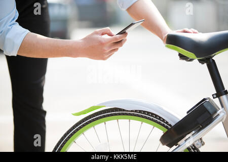 Die jungen Chinesen das Scannen eines QR-Code einen Anteil Bike zu entsperren. Stockfoto