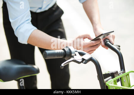 Die jungen Chinesen das Scannen eines QR-Code einen Anteil Bike zu entsperren. Stockfoto