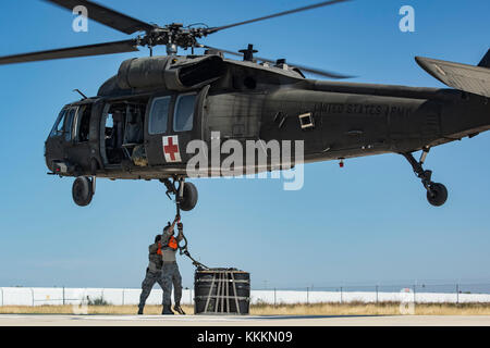 Flieger vom 26. Antenne Anschluss Squadron eine A-22 cargo Tasche mit 2.000 Pfund von "Hilfsgütern", die die Ladung Haken des UH-60 Black Hawk Hubschrauber von Soldaten aus Texas Army National Guard Firma C geflogen, 2-149 Luftfahrt während des Betriebs Alamo Evakuierung November 18, 2017, Martindale Army Airfield, Texas. 36.000 Pfund von Fracht und 27 Passagiere wurden als Teil der Schlinge legen und medizinische Evakuierung transportiert. (U.S. Air Force Foto von älteren Flieger stürmischen Archer) Stockfoto